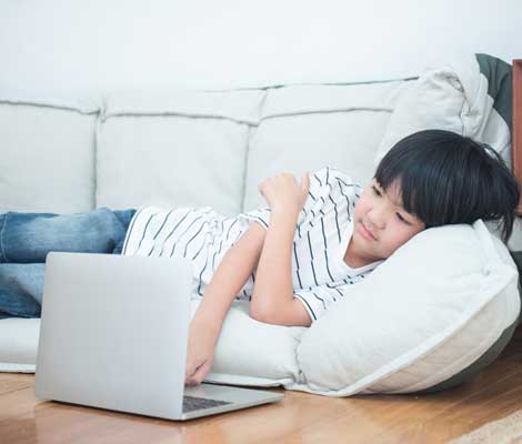 child uses laptop unattended while lounging at home