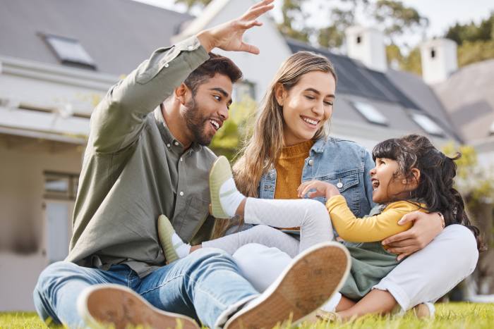 Parents playing with their child outside their house.