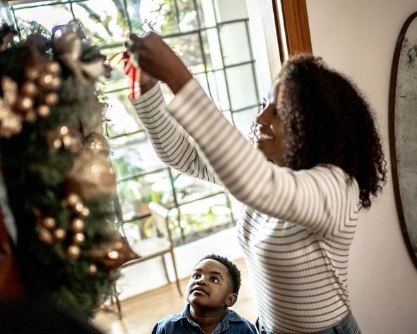 mother and child hanging a wreath on the door