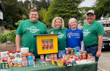 Volunteers smiling with a table full of food donations.