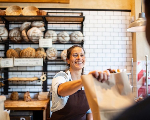 Bakery owner handing a bag to a customer