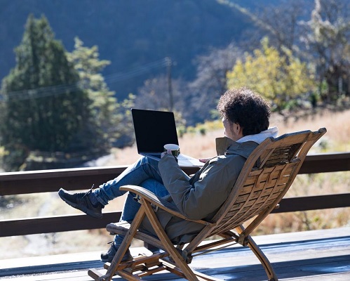 Man sitting outside with laptop and coffee